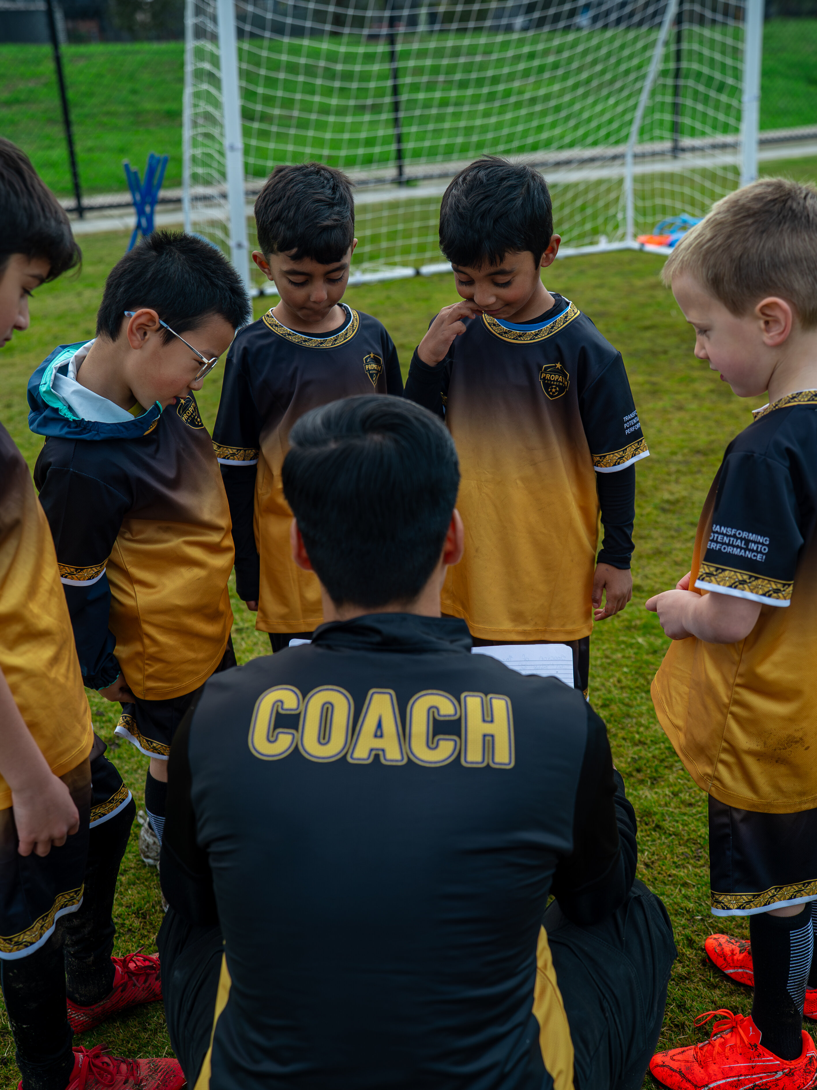 Young players gathered around a coach during a tactical discussion
